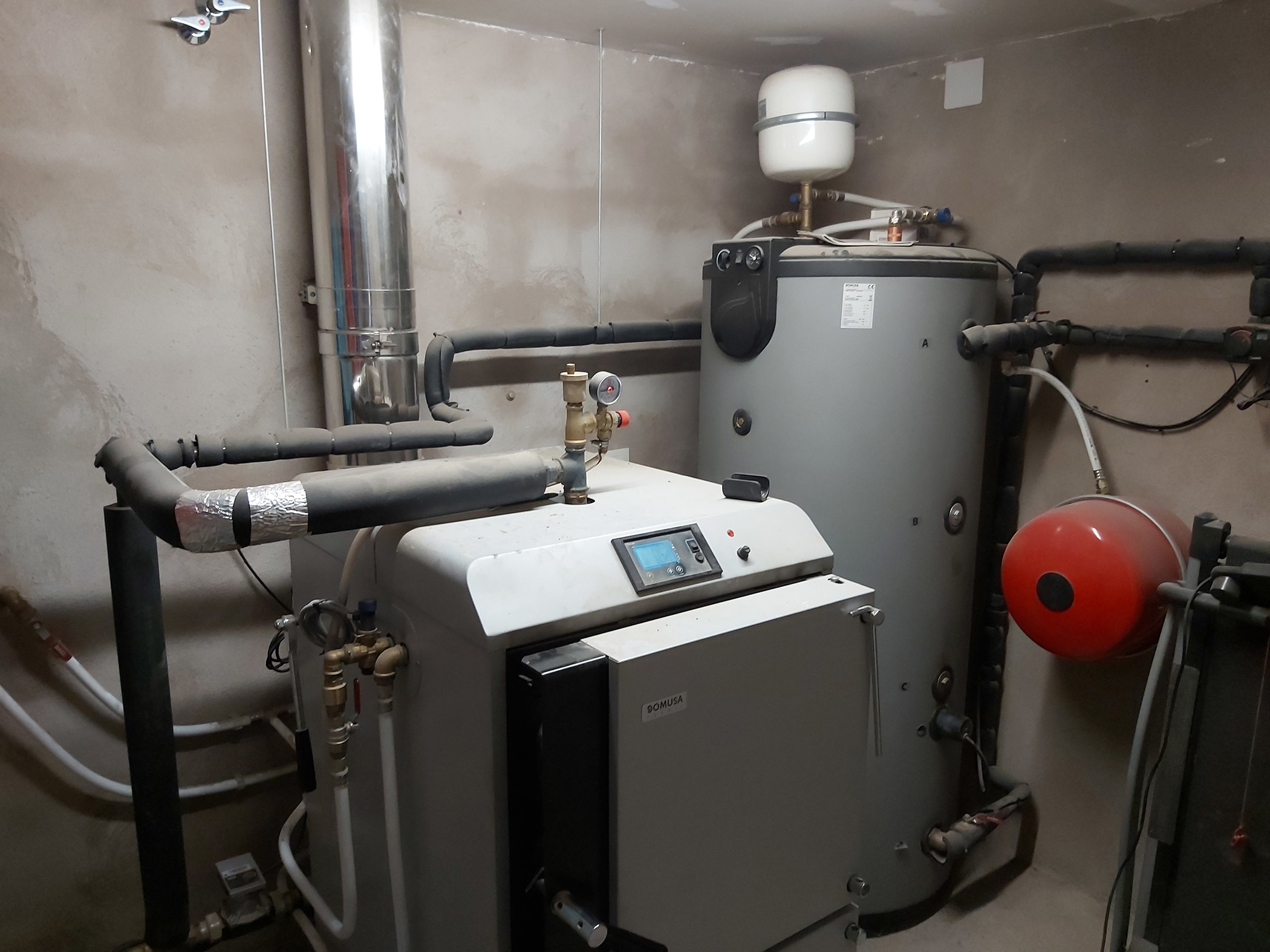 Sala técnica con caldera, depósito acumulador y sistema de calefacción instalado.