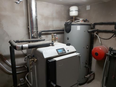 Sala técnica con caldera, depósito acumulador y sistema de calefacción instalado.