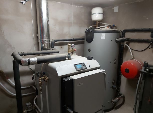 Sala técnica con caldera, depósito acumulador y sistema de calefacción instalado.