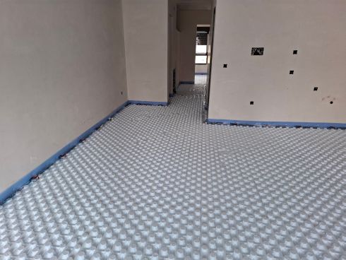 Interior de vivienda en obra con instalación de suelo radiante en proceso.